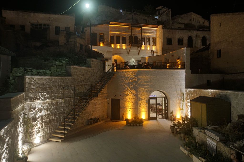 A stone staircase leading to a building with illuminated windows and doors. - Yoruk Stone House (Avanos)