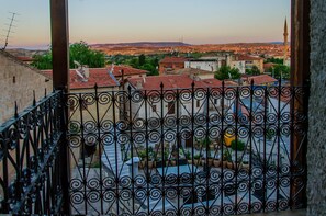 A balcony with wrought iron railings overlooking a residential area with red-tiled roofs and a mosque with a minaret. - Yoruk Stone House (Avanos)