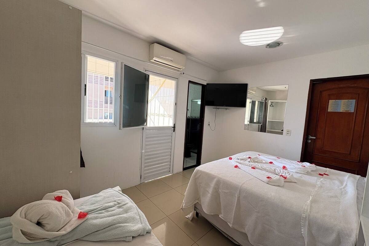 Habitación de hotel con cama, televisión montada en la pared, puerta y ventana.