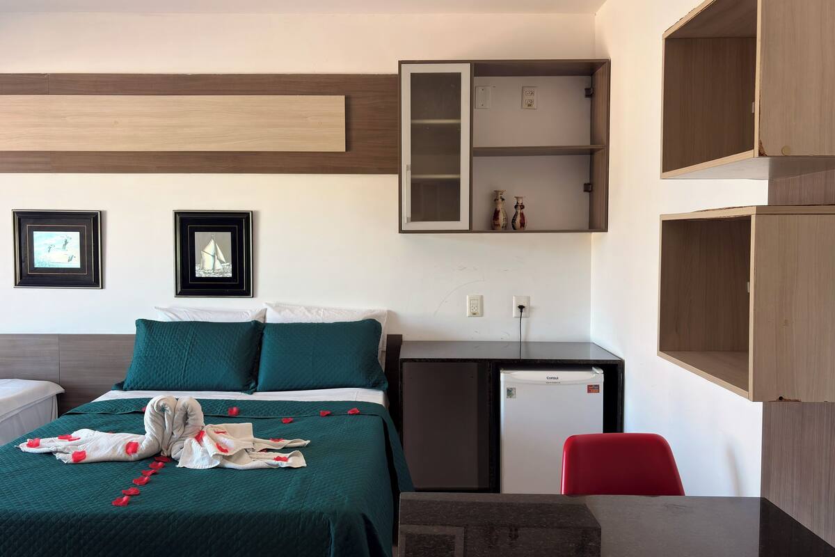 Habitación de hotel con cama, escritorio y silla. Hay dos cuadros en la pared.