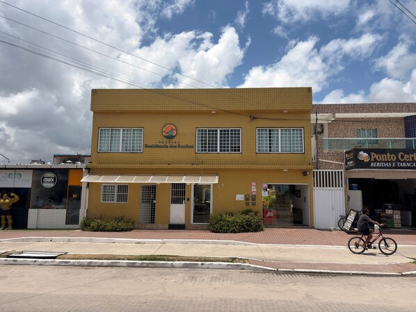 A two-story building with a yellow facade, a visible entrance, and a sign for 'Ponto Certo Beidas e Tabaca'.