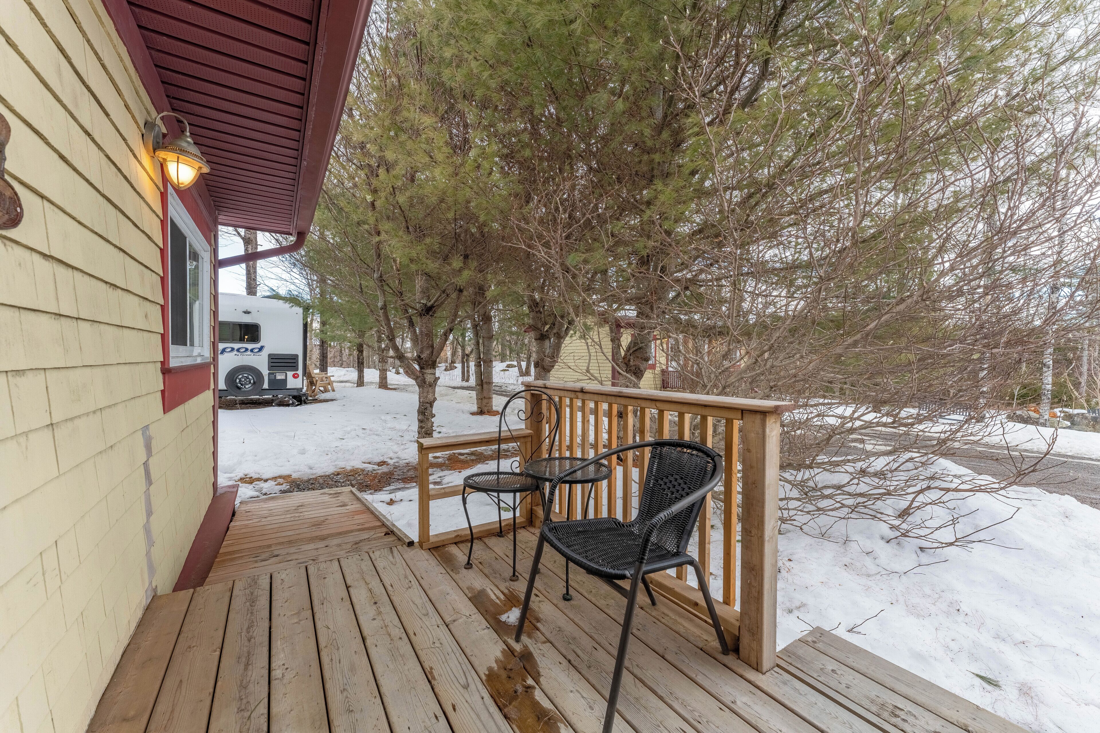A wooden deck with a railing, a chair, and a table.