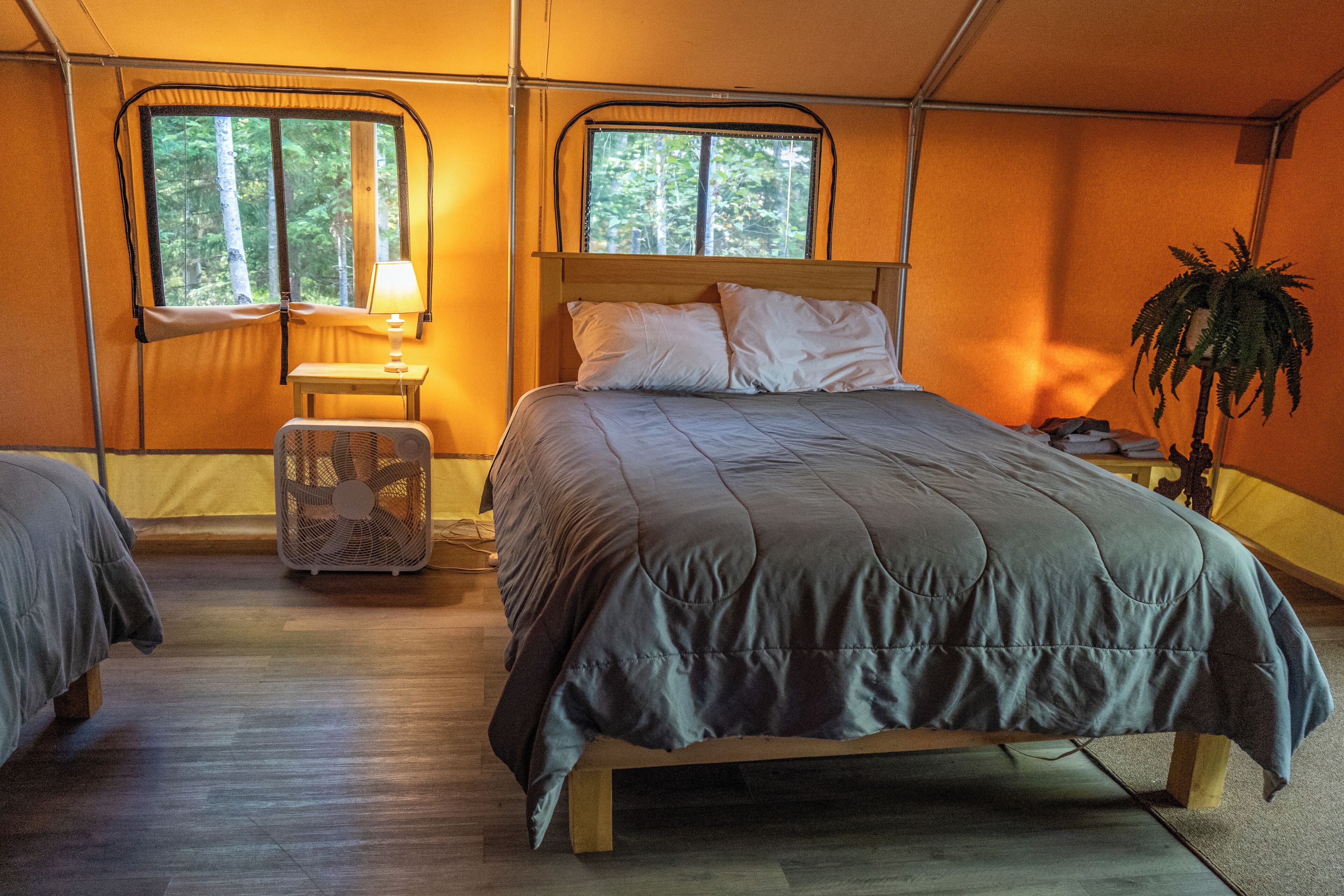 Ein Zelttraum mit Bett, Ventilator und Fenster.