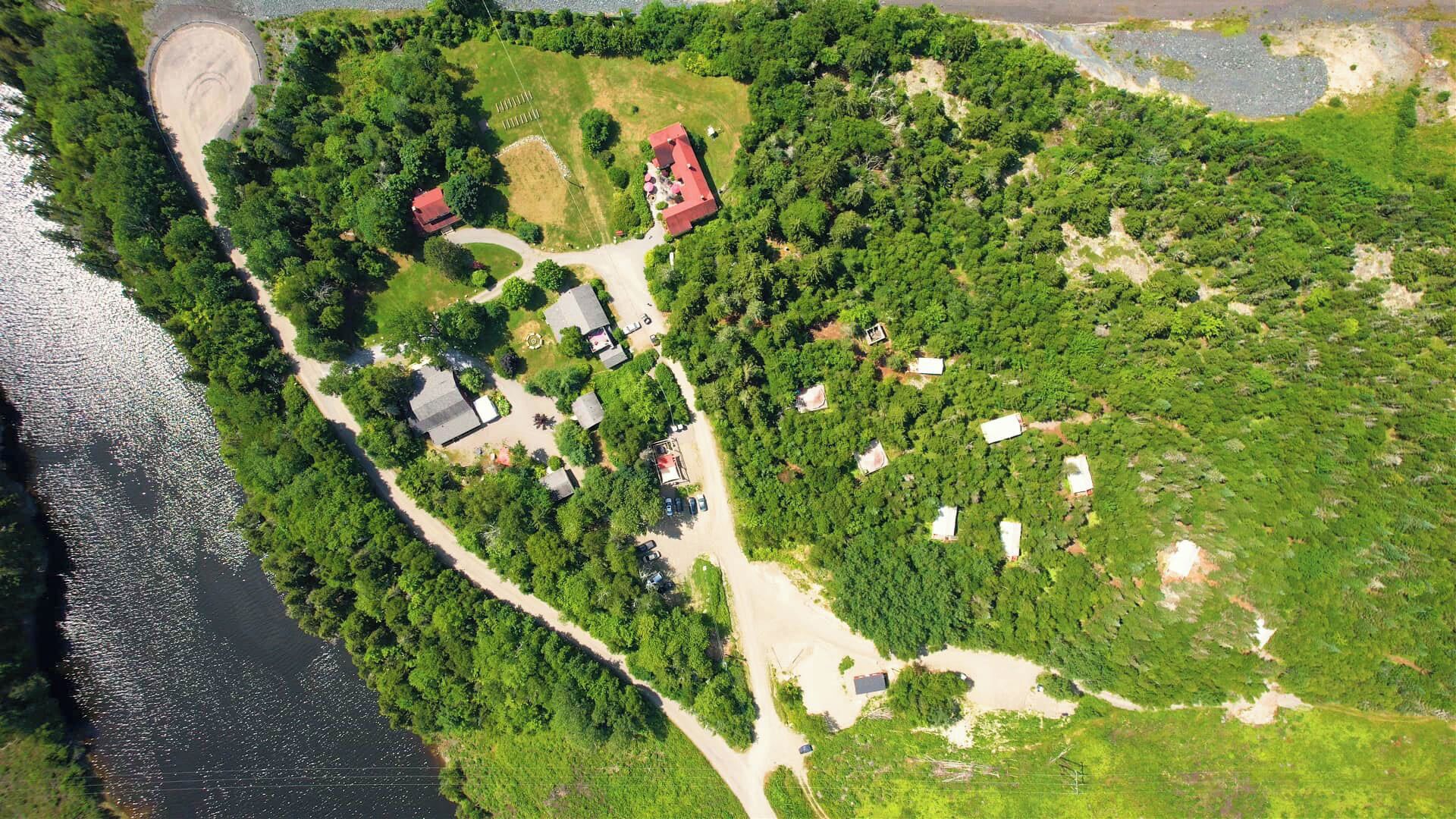 An aerial view of a coastal property with multiple buildings, a winding road, and a beach area.