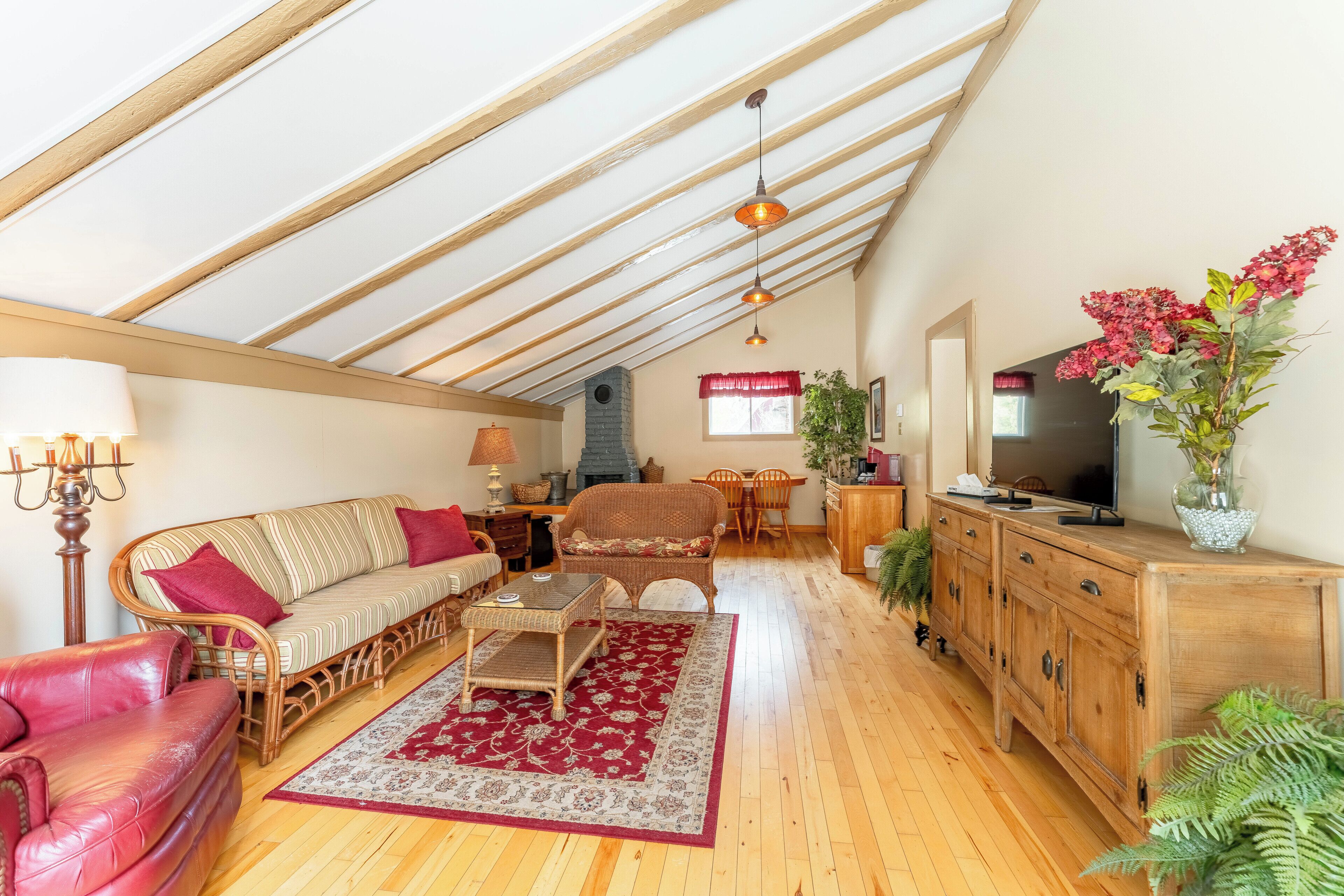Un salon spacieux avec un plafond haut, un plancher en bois, un canapé, une table basse et un téléviseur.