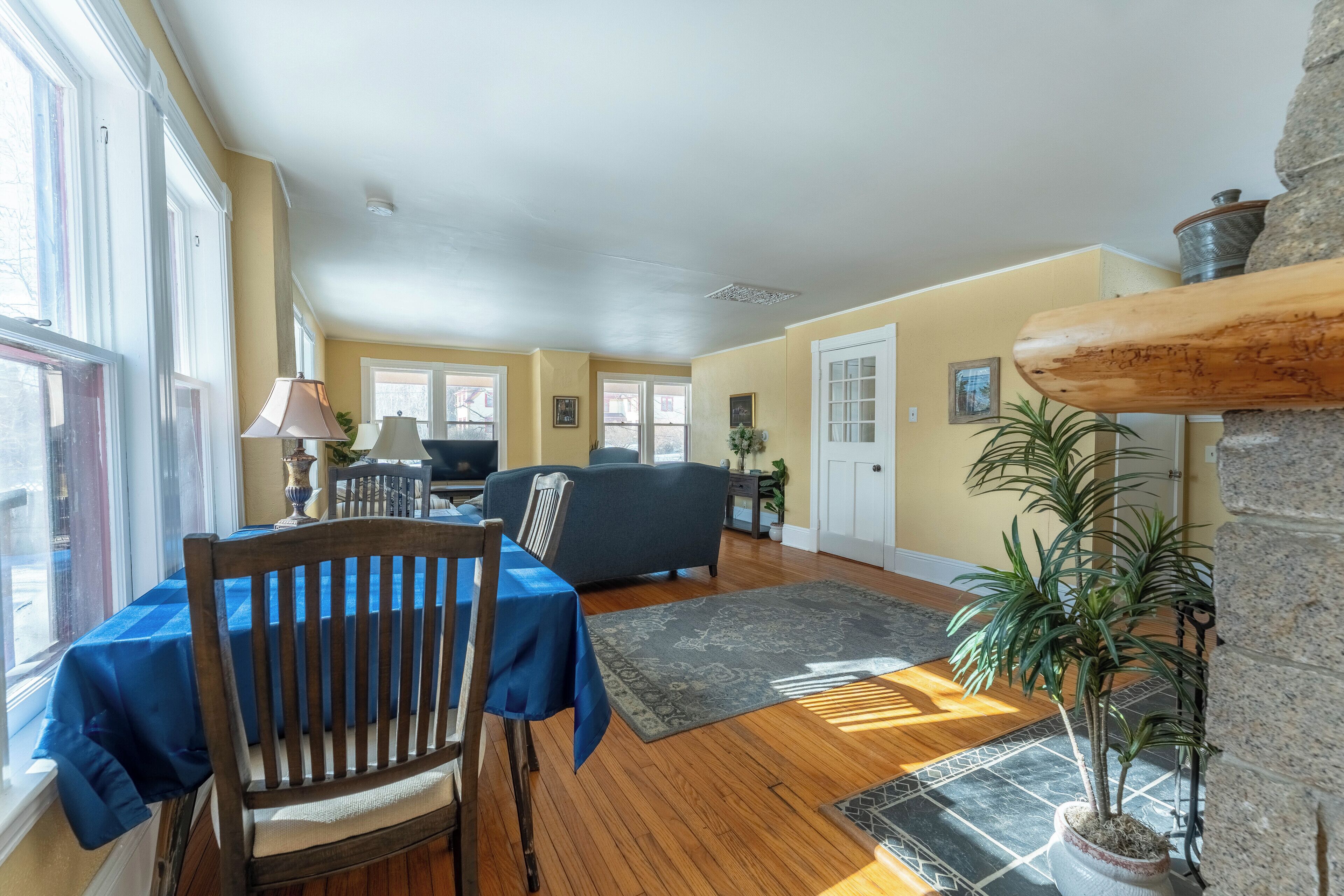 A spacious living room with a dining area, wooden flooring, and a stone fireplace.