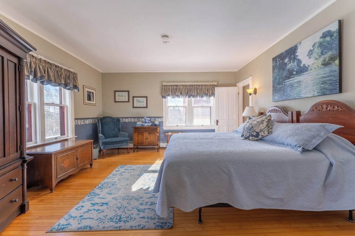 Un dormitorio con una cama grande, cómoda de madera y una silla.