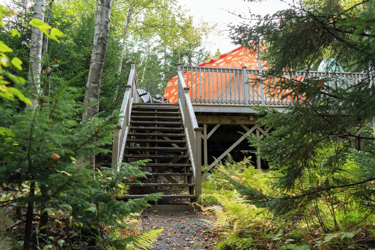 A wooden staircase leading to a covered wooden structure with a metal railing.