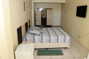 A bedroom with a bed, a wardrobe, a television, and a small desk. - Comfoort Hotel (Volta Redonda)