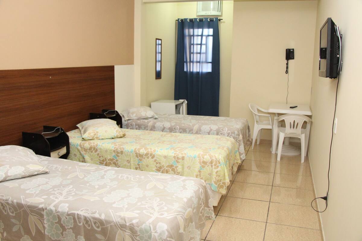 A hotel room with two beds, a desk, a chair, a telephone, and a window with curtains.
