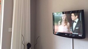A television mounted on a wall displaying a news program. - Harare City 1-bed Apartment (Harare)