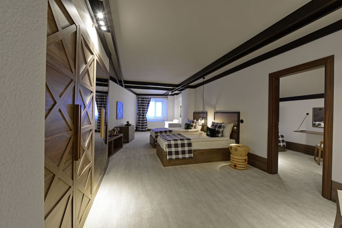 Une chambre à coucher avec un grand lit, des tables de chevet, une armoire en bois et une fenêtre avec des rideaux.