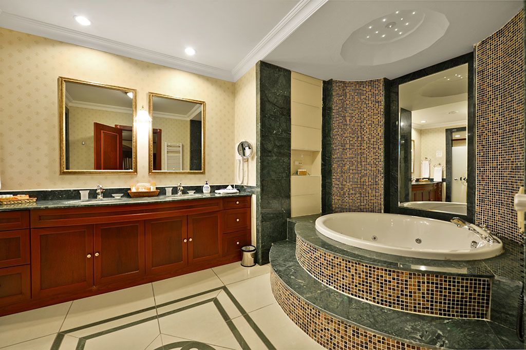 Un baño moderno con una bañera grande, un lavabo doble con espejos y un salpicadero de azulejos estampados.