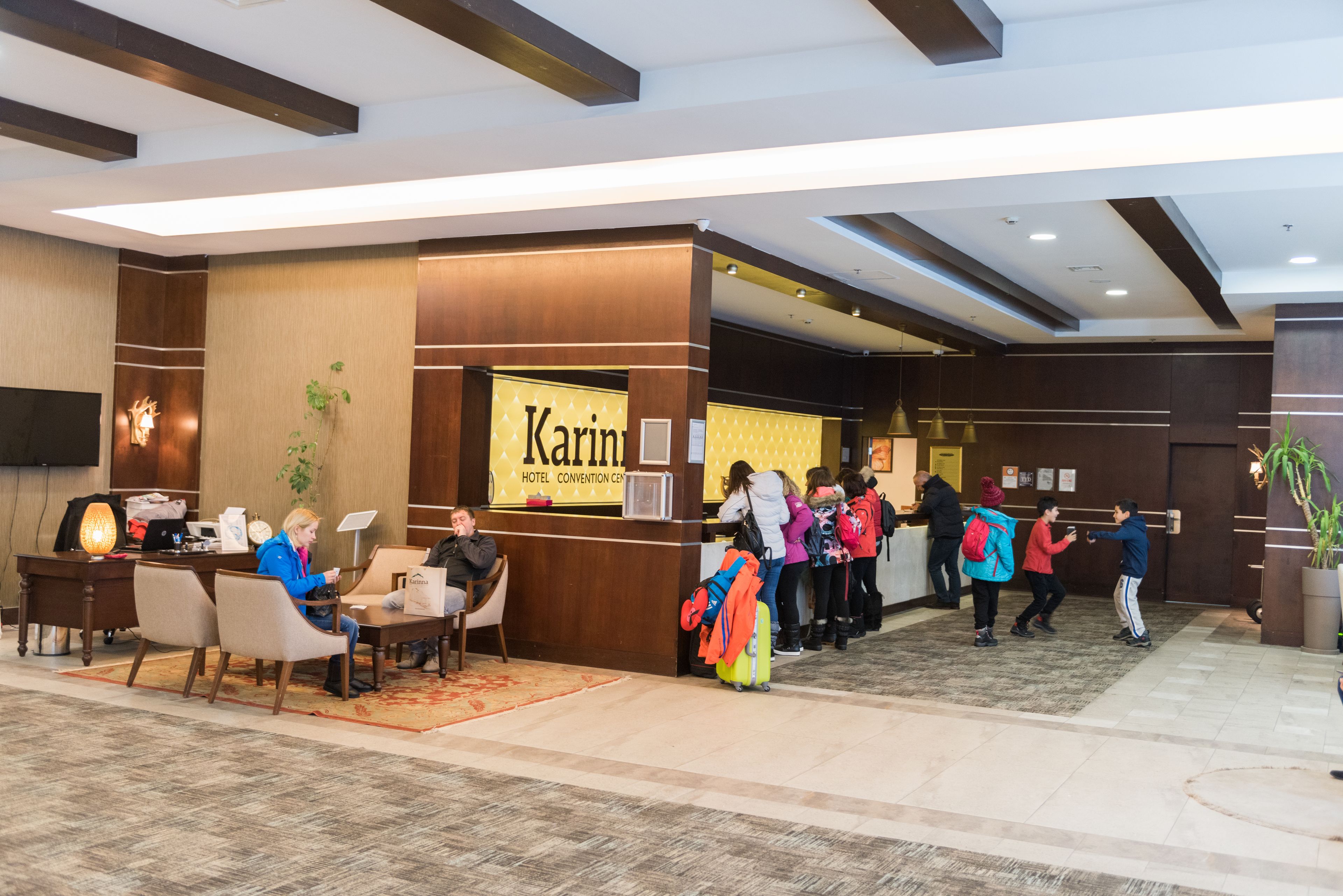 Zona de recepción de un hotel con un mostrador de recepción, área de descanso y un cartel para el Centro de Convenciones Karint Hotel.