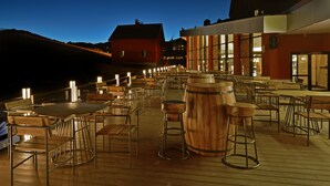 An outdoor dining area with wooden tables and chairs, bar stools, and a large wooden barrel. - Karinna Hotel Uludag (Bursa)