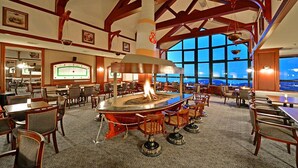 A spacious dining area with a central fire feature, wooden beams, large windows, and a view of the outside. - Karinna Hotel Uludag (Bursa)