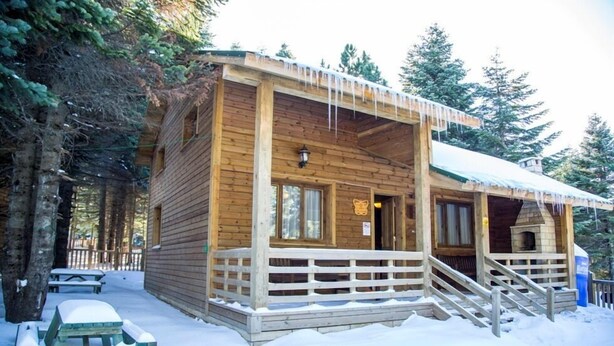 A wooden cabin with a porch, wooden benches, and a chimney. - Uludag Orman Koskleri (Bursa)