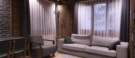 A cozy living room with a sofa, chairs, a coffee table, and a fireplace.