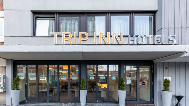 The exterior of a TRIP INN HOTEL with large glass doors, potted plants, and a modern facade. - Trip Inn Hotel Münster City (Münster)