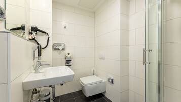 Un baño moderno con lavamanos, inodoro y cabina de ducha de vidrio.