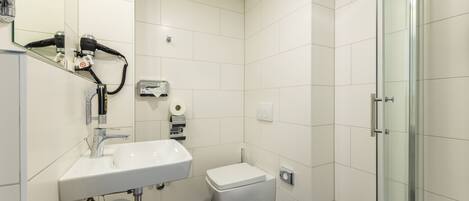 A modern bathroom with a white sink, toilet, and glass shower enclosure.
