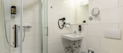 A modern bathroom with a glass shower enclosure, a white sink, and a mirror.