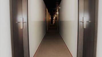 Un pasillo estrecho con alfombra, con puertas de madera a ambos lados, que conduce a un extremo oscuro.