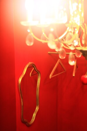 Un muro rosso con uno specchio appeso e una decorazione geometrica.