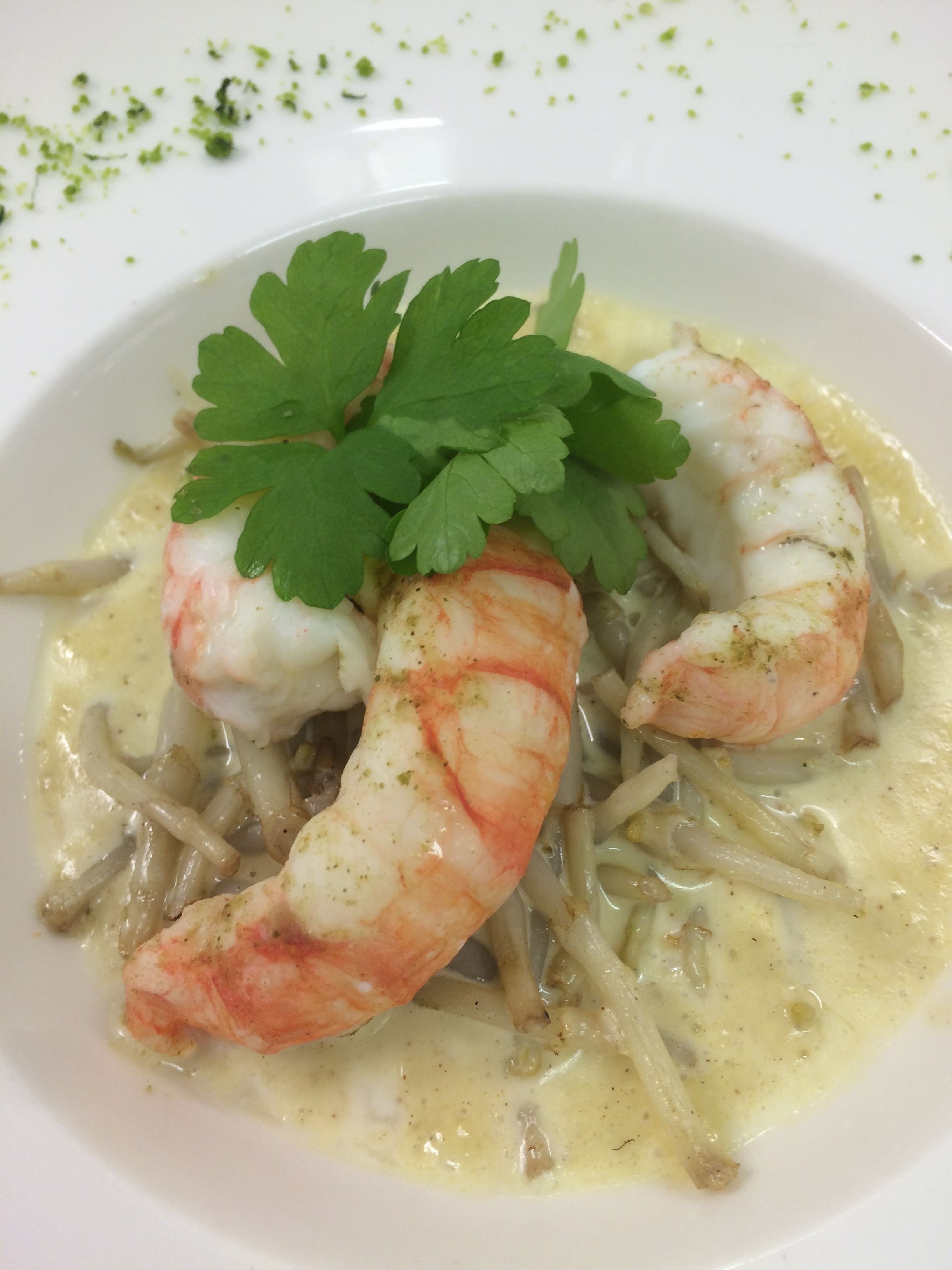 Un plato de comida con camarones y una guarnición de perejil.