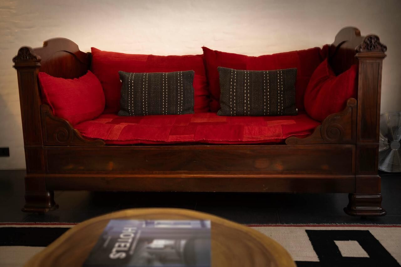 Ein Holzsofa mit roten Kissen und gemusterten Kopfkissen.