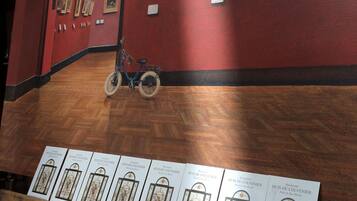 Una habitación con piso de madera, una bicicleta y cuadros en la pared.