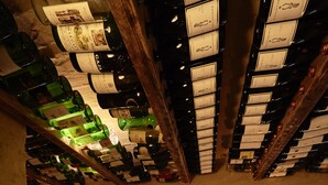 Un bar con barriles de madera, botellas en el techo y taburetes.