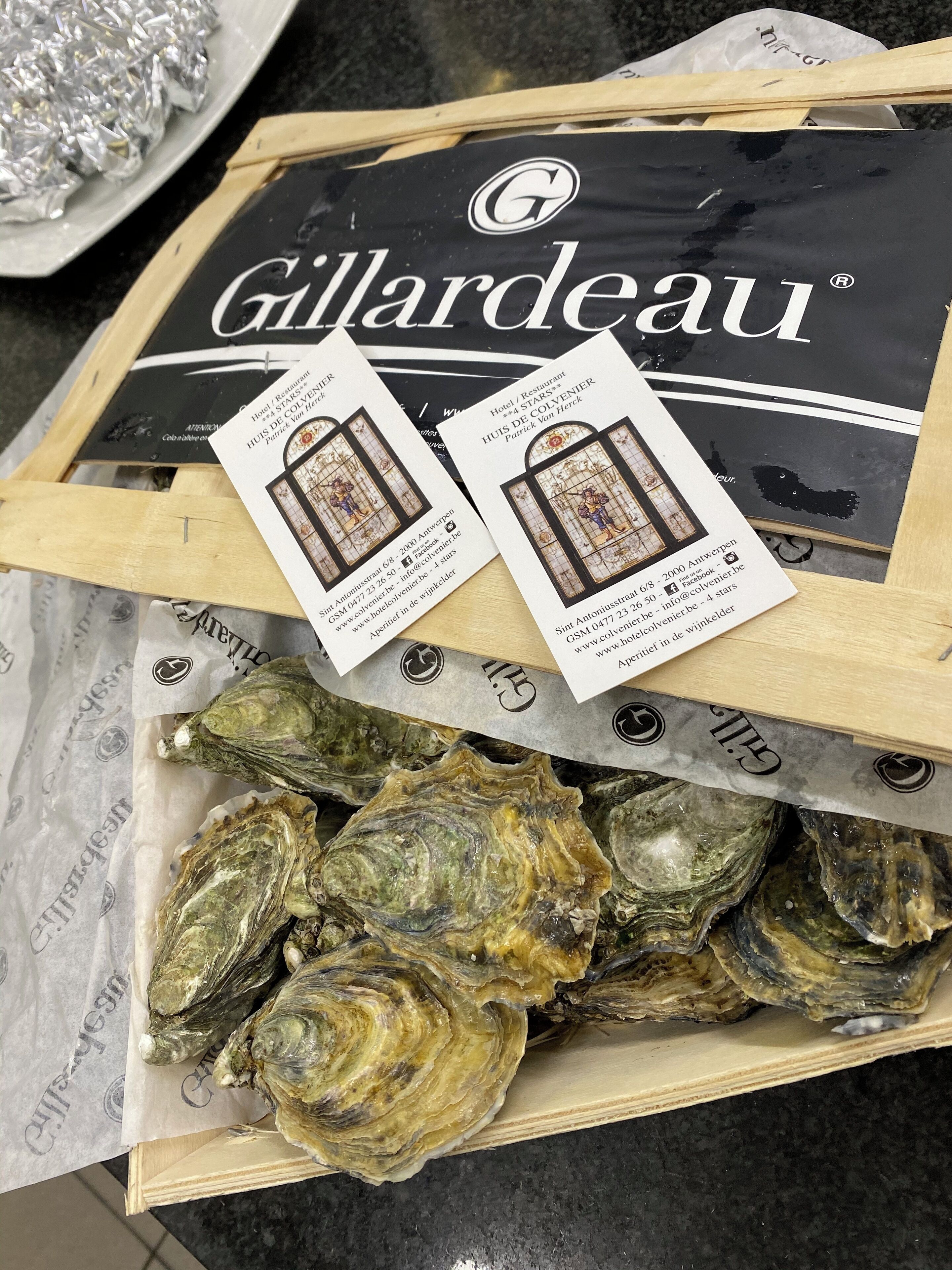 A wooden box containing oysters with a Gillardeau brand label and informational cards.
