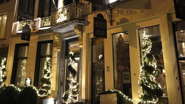 Un hotel con un cartel que indica que es restaurante y hotel. Hay banderas y luces en el edificio.