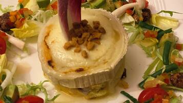 A white plate with a baked dish surrounded by a colorful salad.