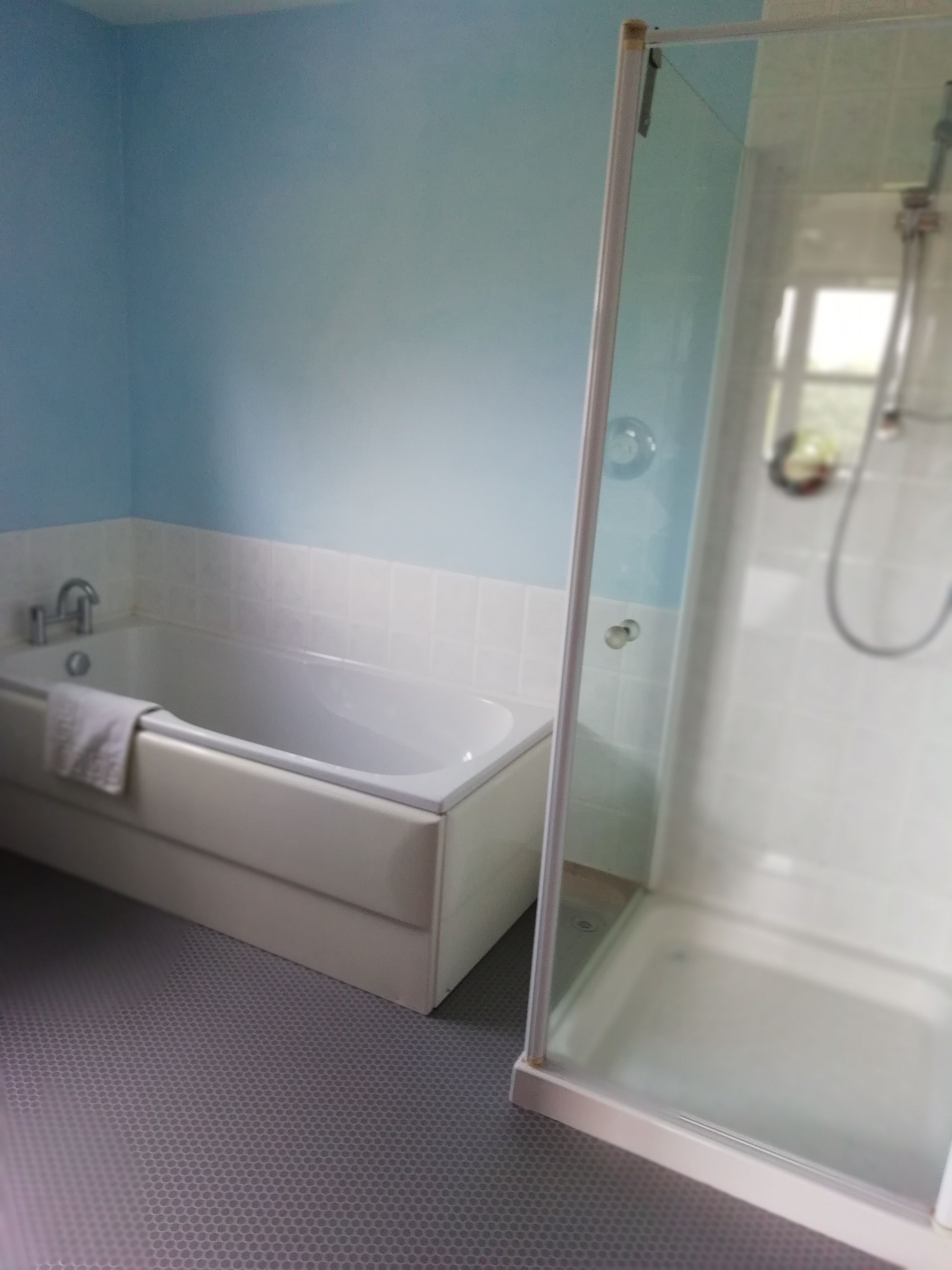 A bathroom with a bathtub, a glass shower enclosure, and a tiled floor.