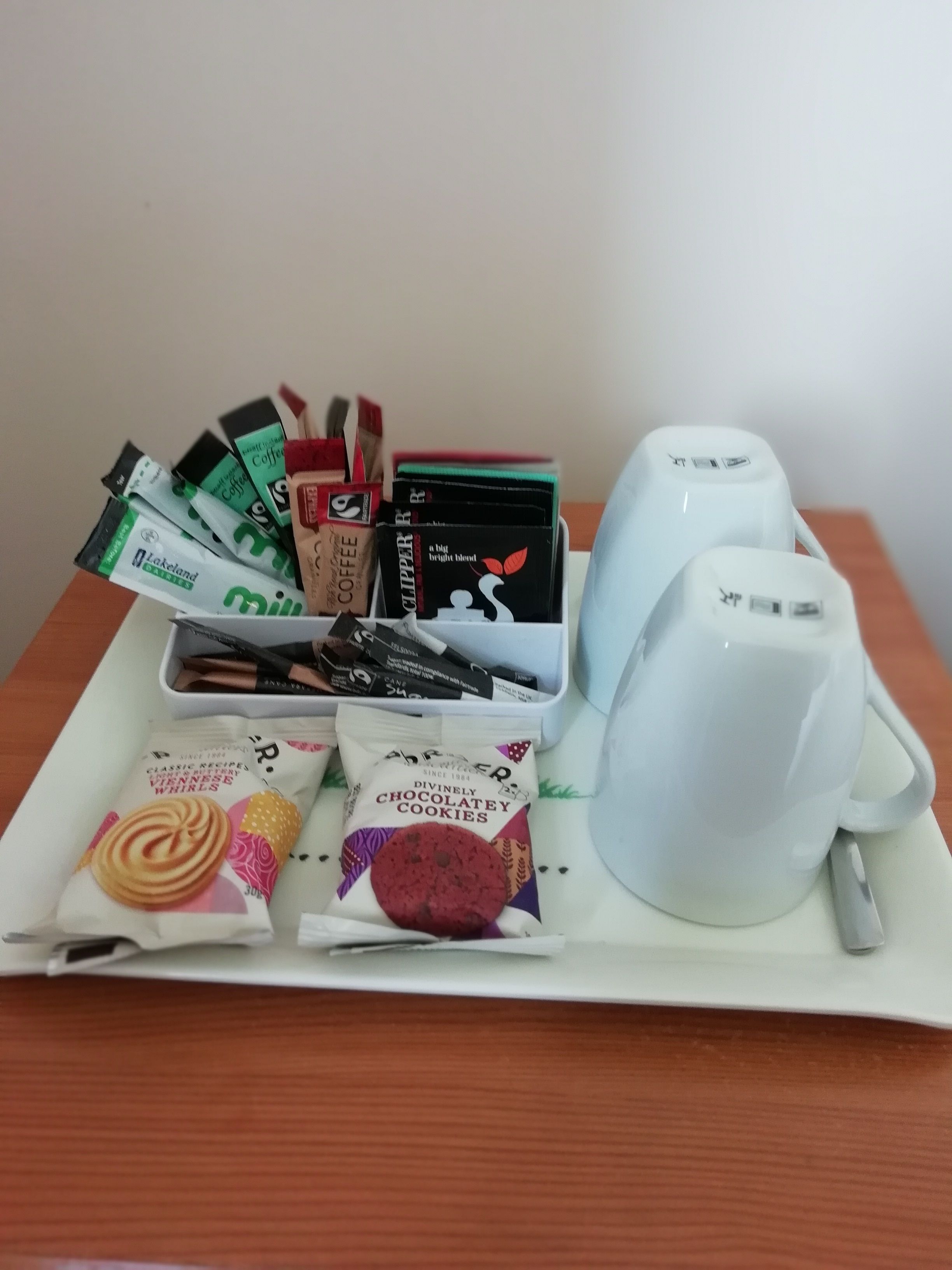 A tray with a white mug, coffee packets, and a packet of chocolate cookies.