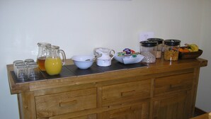 A breakfast bar with various food and drink items, including a pitcher of orange juice, bowls, and containers of cereal and granola. - Balhousie Farm (Leven)