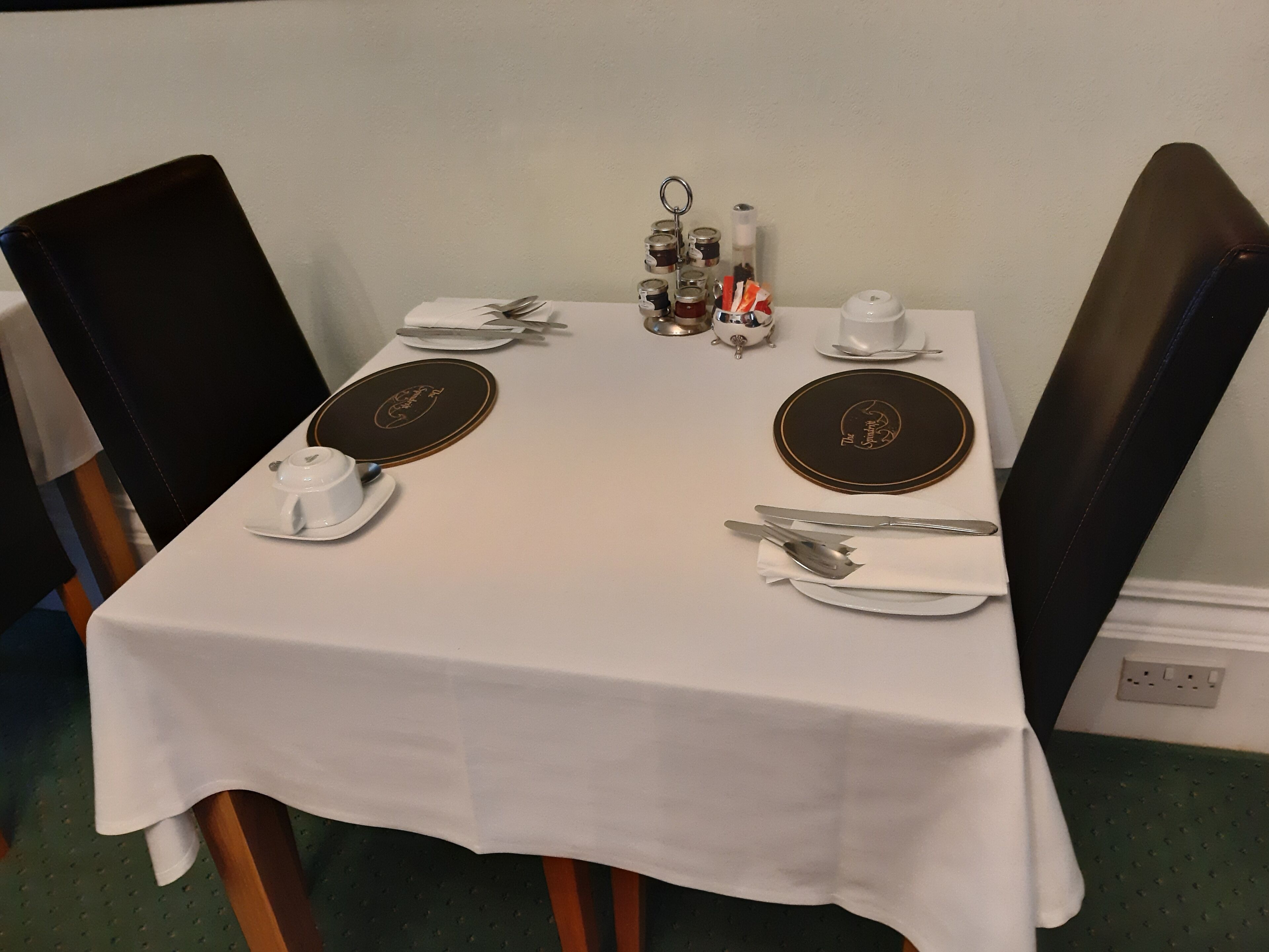A dining table set with plates, cutlery, and a teapot.
