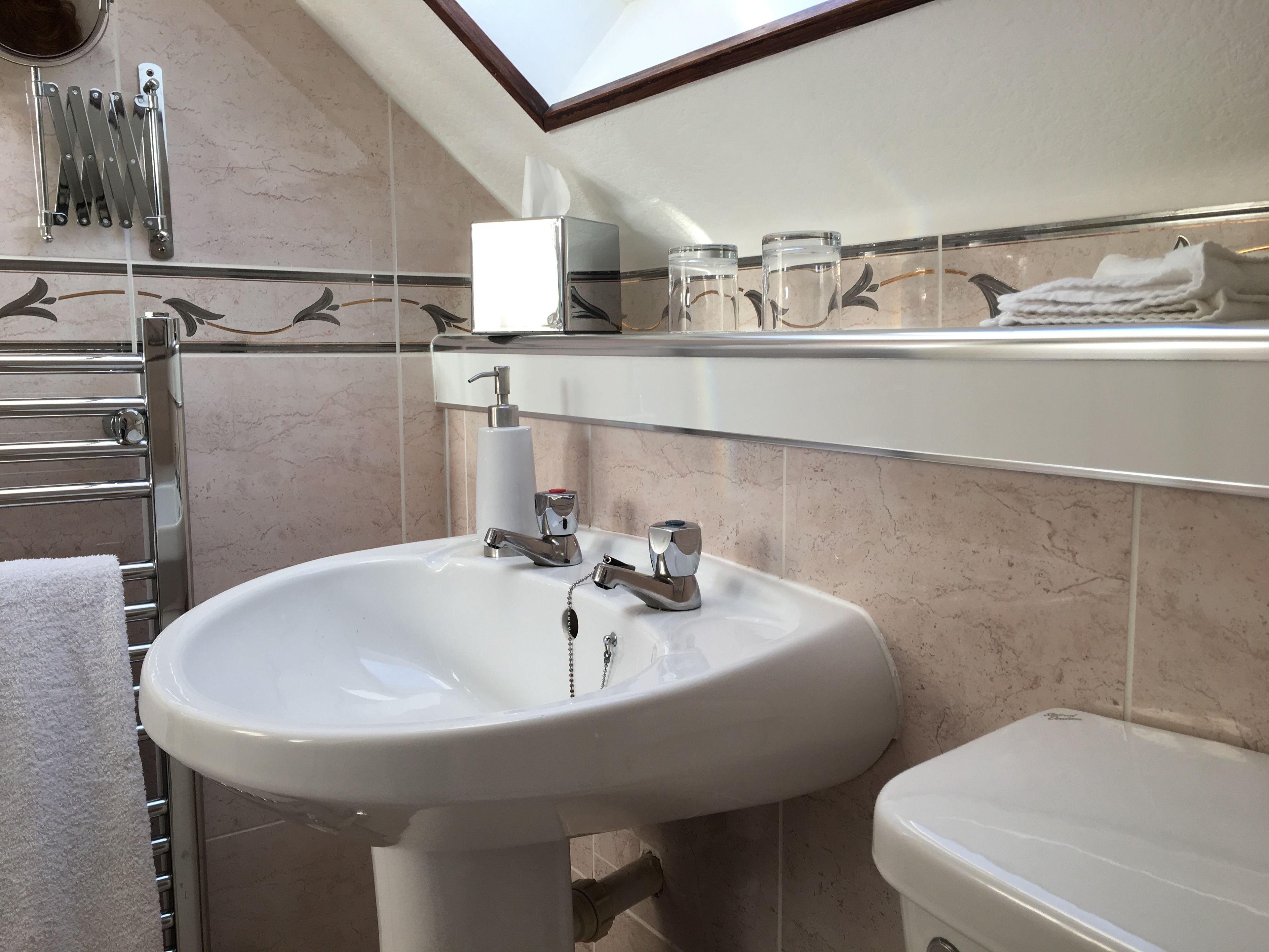 A bathroom with a white sink, a toilet, a towel rack, and a mirror.