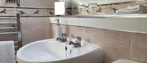 A bathroom with a white sink, a toilet, a towel rack, and a mirror.