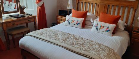 Un dormitorio ordenado con una cama de madera, una mesita de noche a juego y un escritorio con una silla.