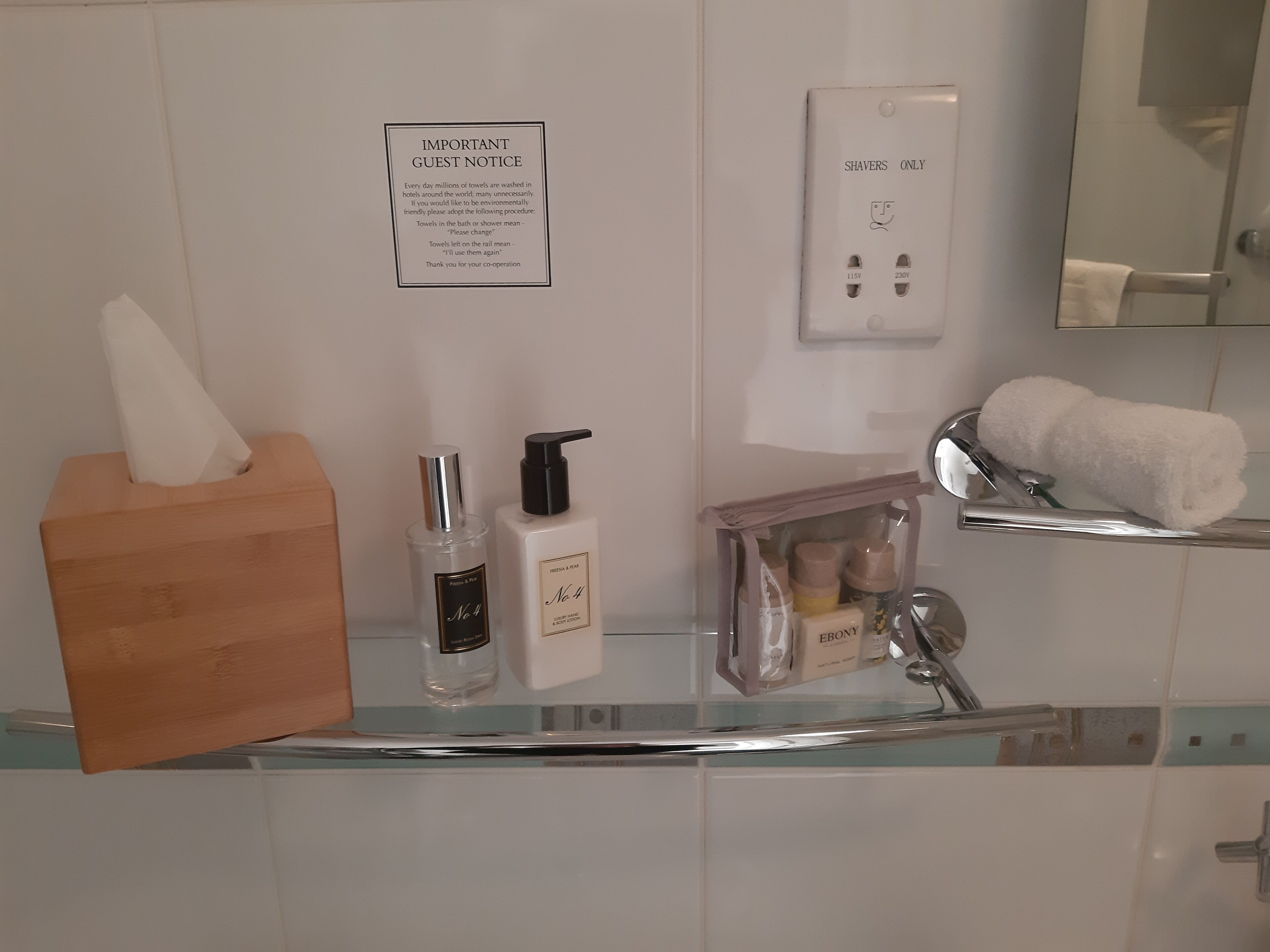 Un baño con dispensador de toallas de mano, caja de pañuelos y un cartel que indica a los huéspedes usar únicamente la ducha.