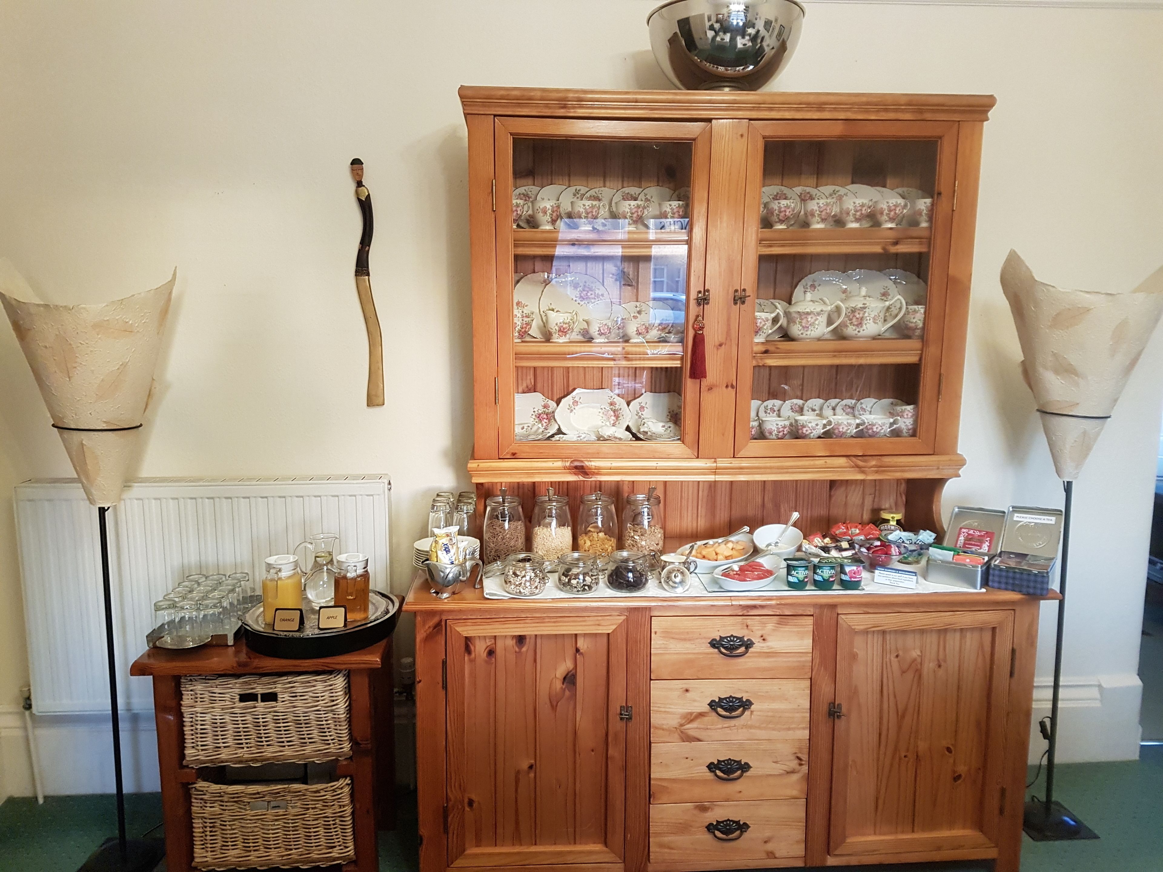 A wooden cabinet with glass doors displaying various kitchen items and utensils.