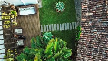 A rooftop garden with a variety of plants, a seating area with a table and chairs, and a small pool.