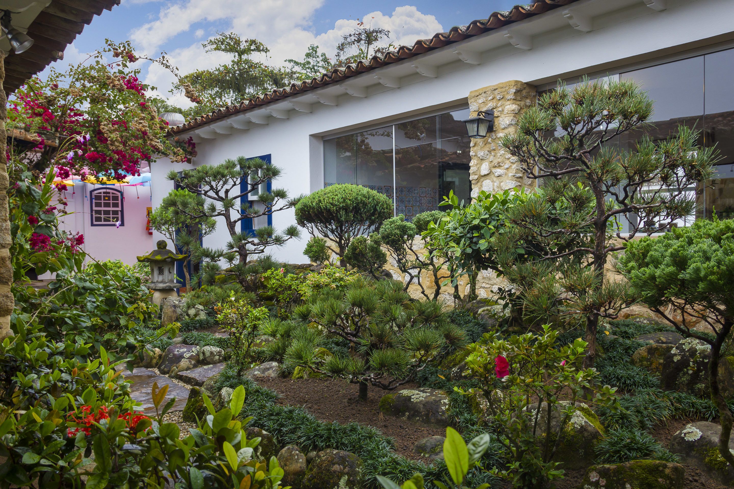 A traditional house with a garden featuring various plants and a small pond.