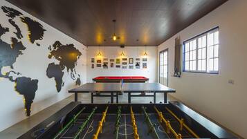 Een kamer met een tafelvoetbaltafel, een biljarttafel en een wereldkaart aan de muur.