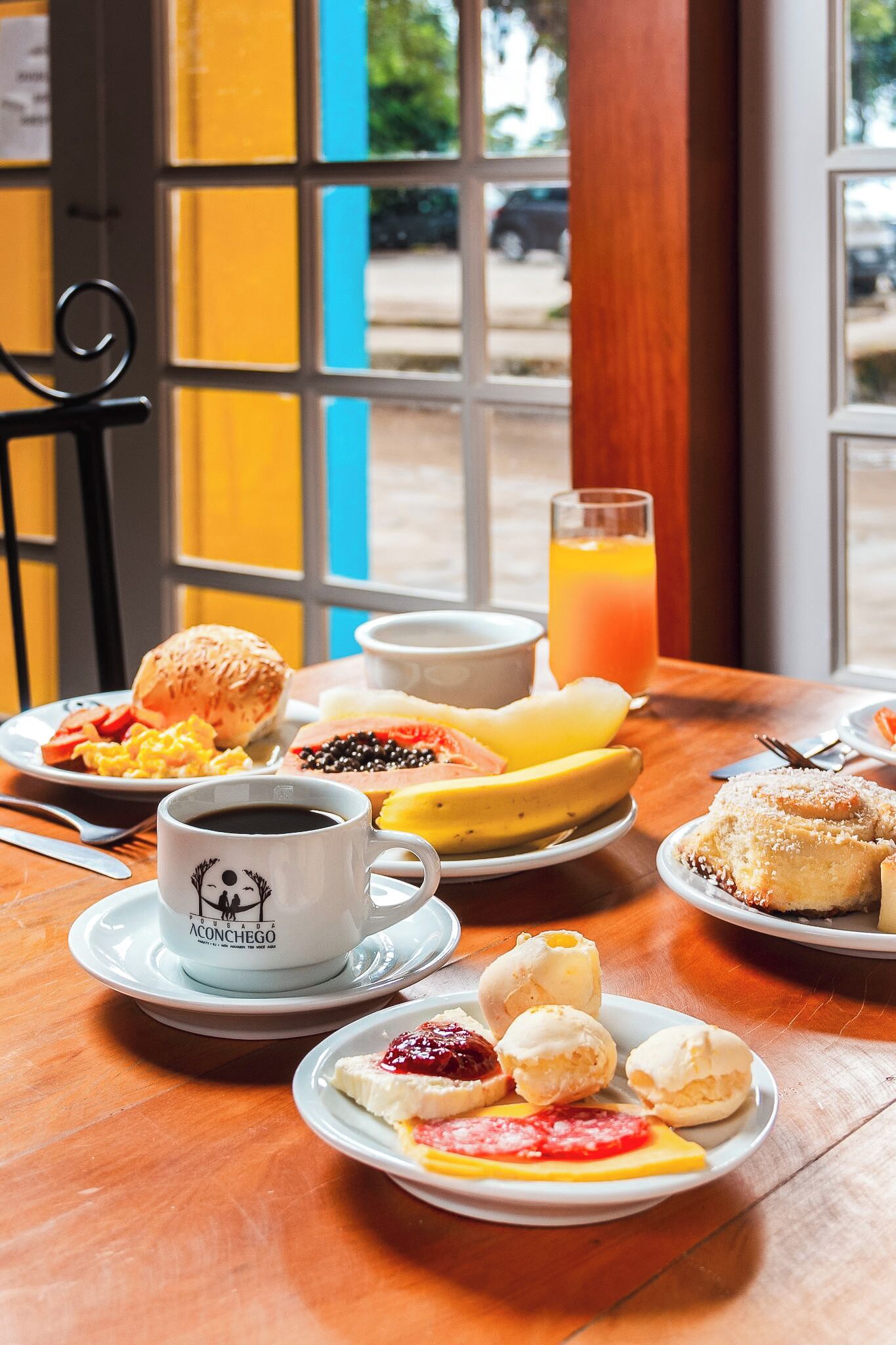 A breakfast table with plates of food, a coffee cup, and a glass of orange juice.