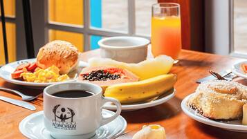 A breakfast table with plates of food, a coffee cup, and a glass of orange juice.