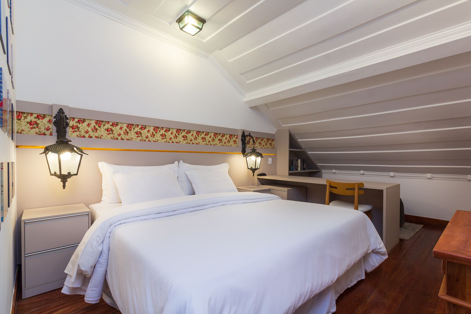 A bedroom with a bed, bedside tables, a desk, and a chair.